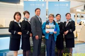 初便搭乗手続き第1号の乗客を囲むUAセフォリア副社長、客室乗務員(UNITED)